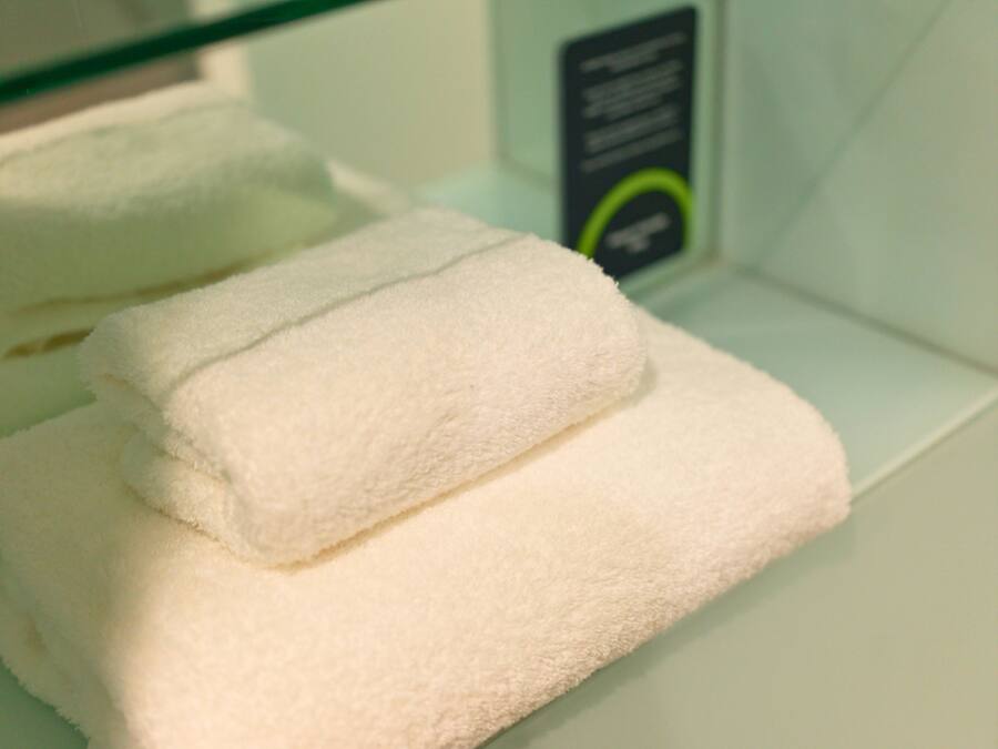 A stack of white towels on a white shelf.