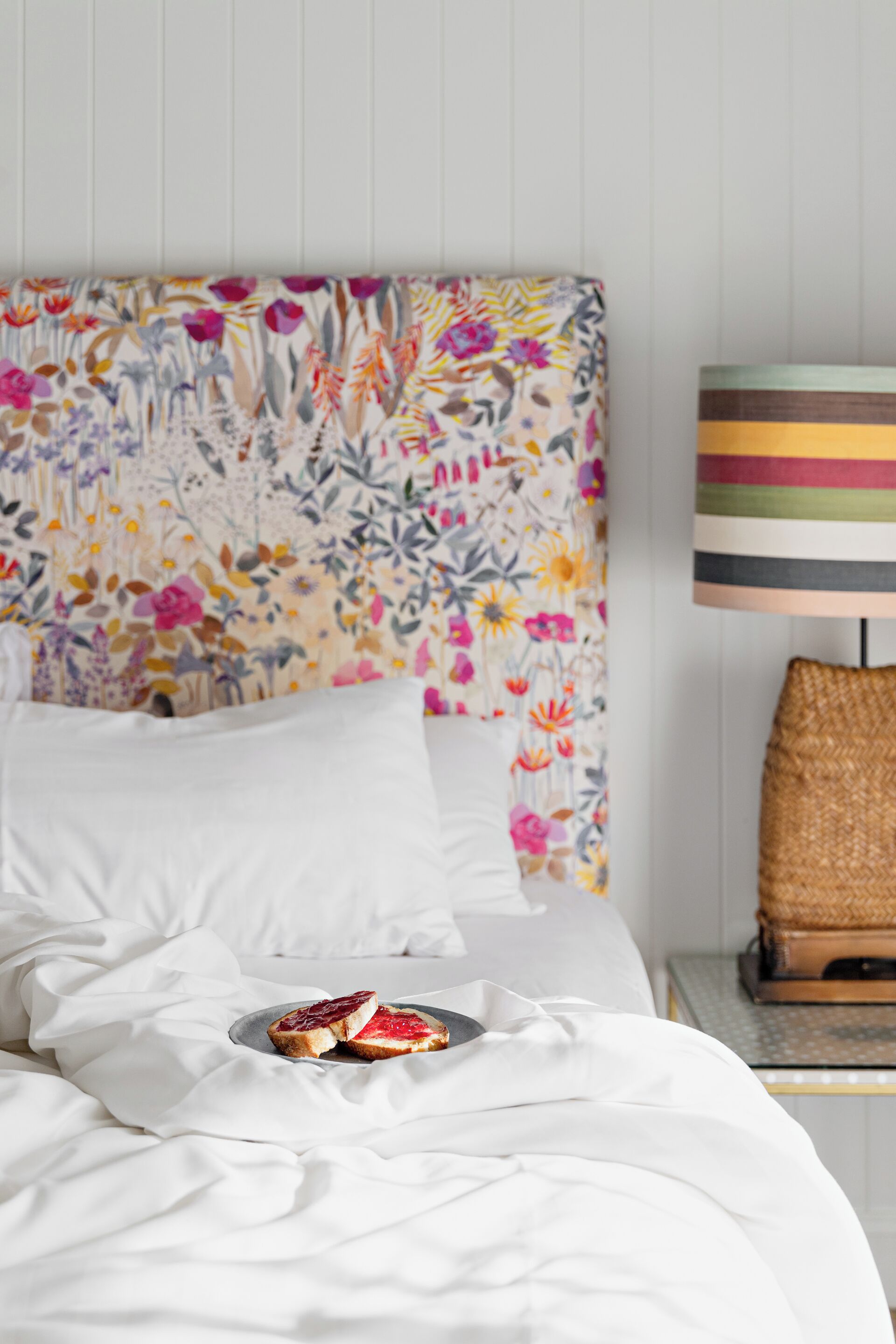 A neatly made bed with white linens and a floral headboard.