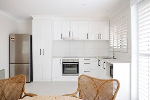 Una cocina moderna con gabinetes blancos, electrodomésticos de acero inoxidable y sillas de mimbre.