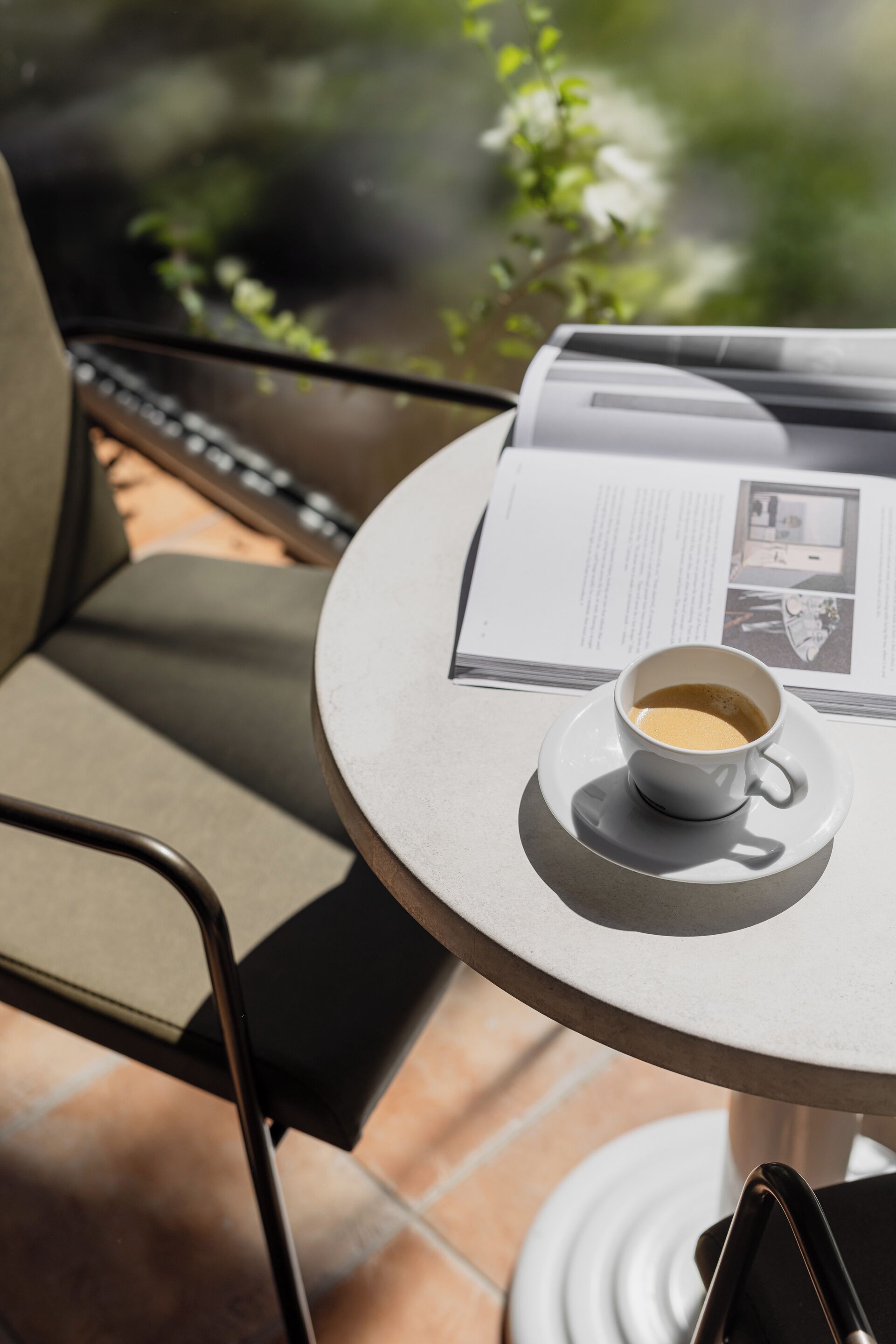 Una mesa redonda con una taza de café y un menú, una silla, y una ventana de vidrio al fondo.