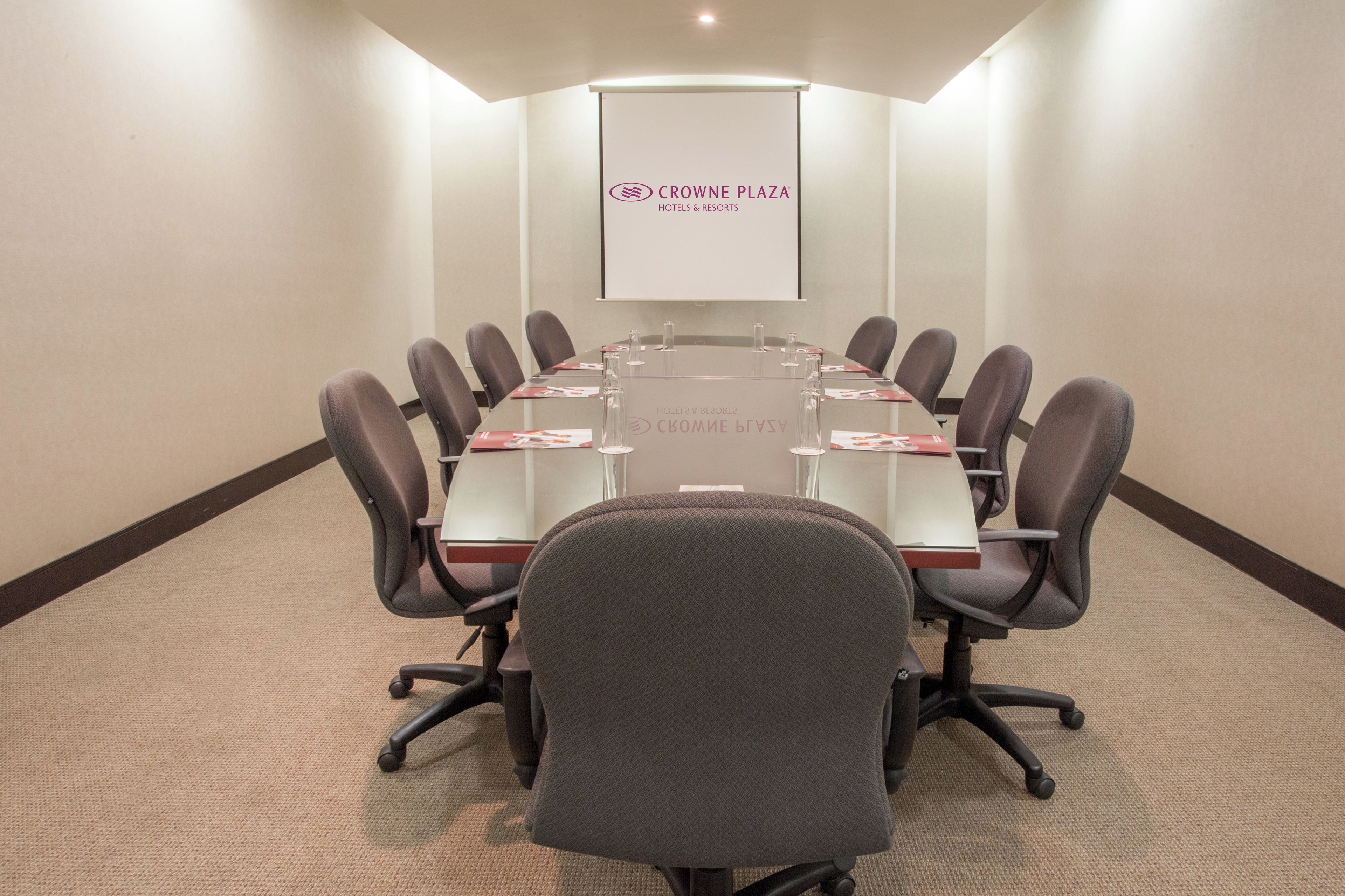 Une salle de conférence équipée d’une longue table, de chaises et d’un écran de présentation.