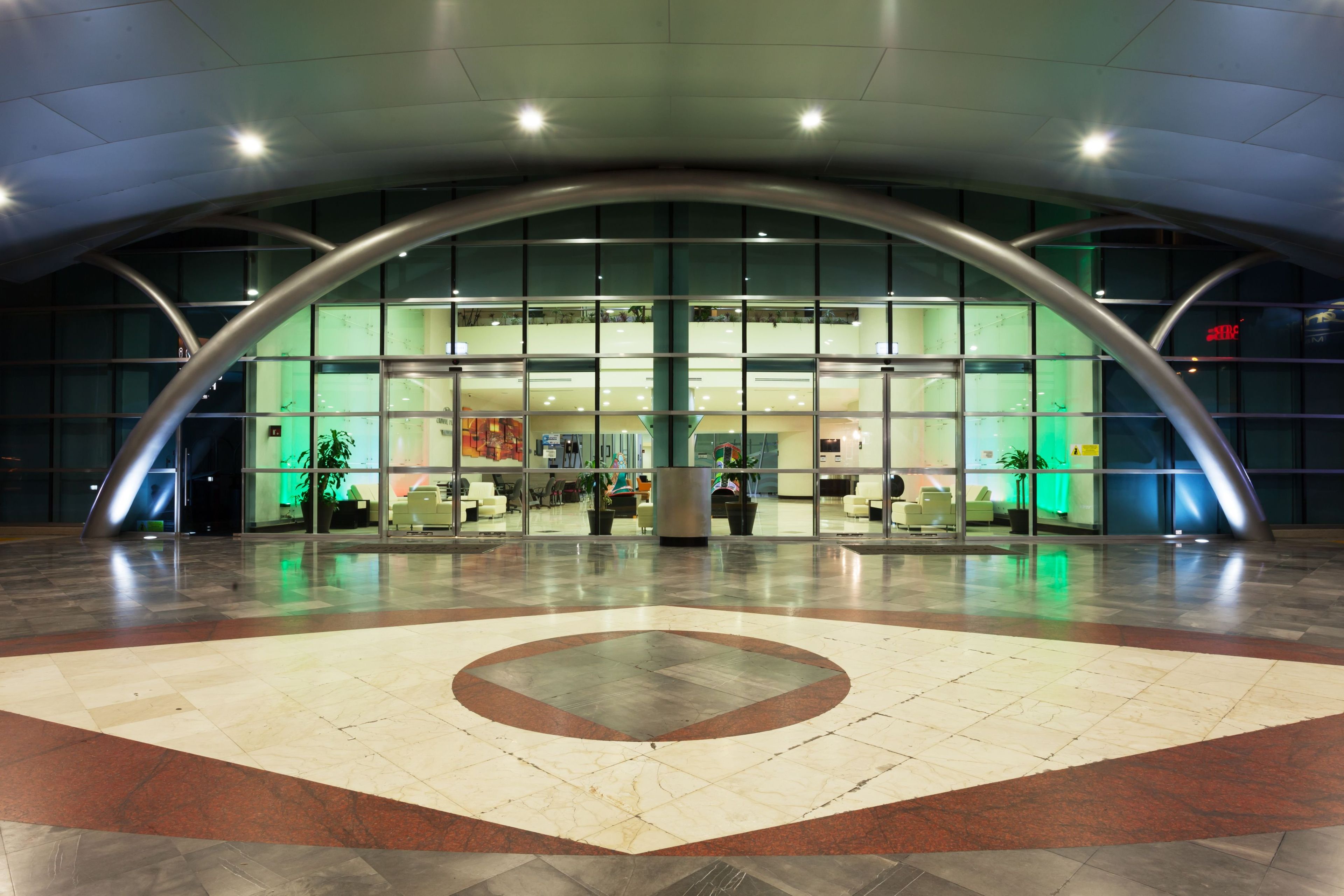 A modern building with a curved glass facade, a central atrium, and a patterned floor.