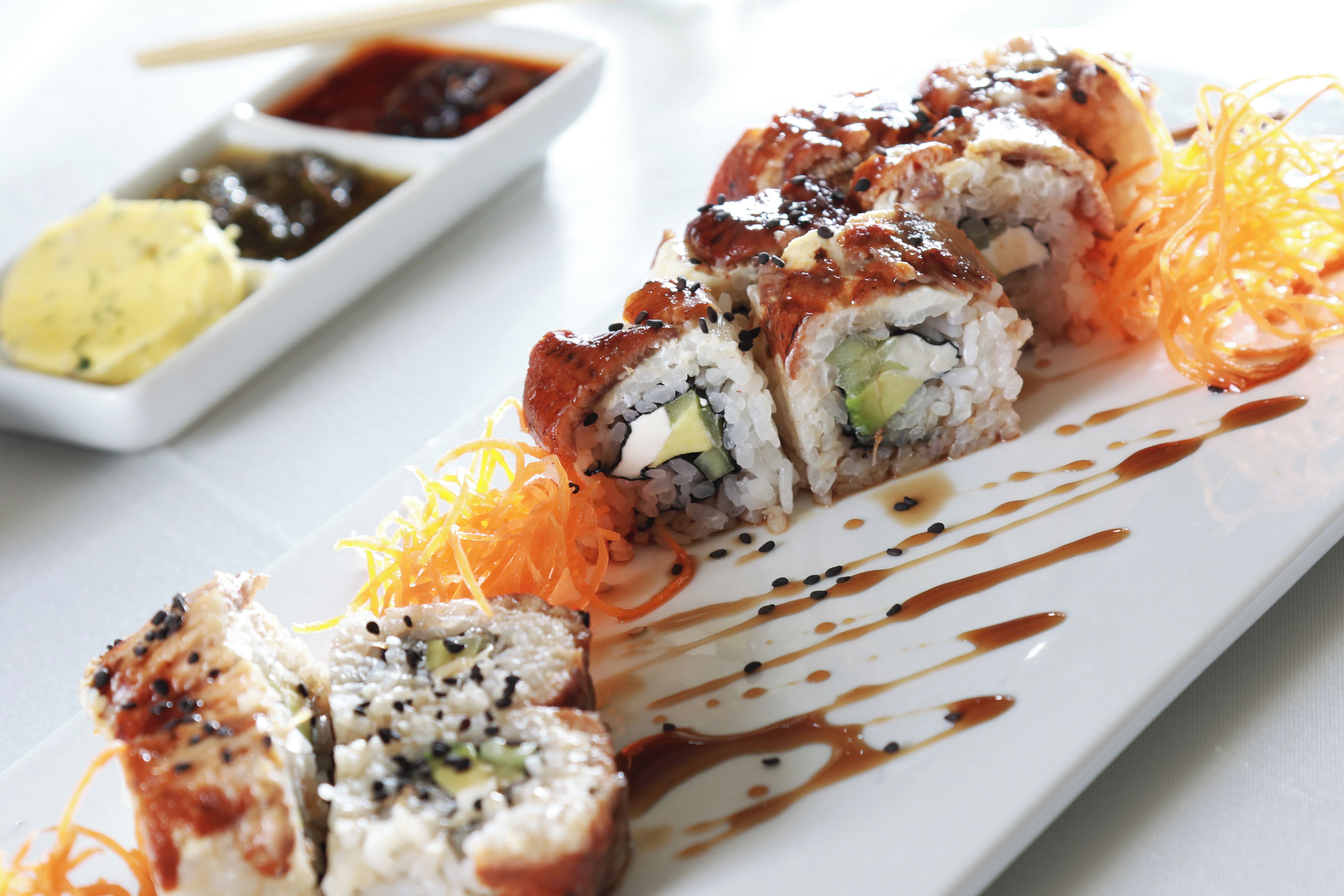 Un plato de sushi con salsa y zanahoria rallada.