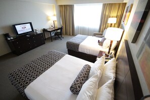 A hotel room with two beds, a desk, a television, and a window with curtains. - Crowne Plaza Leon by IHG (León)