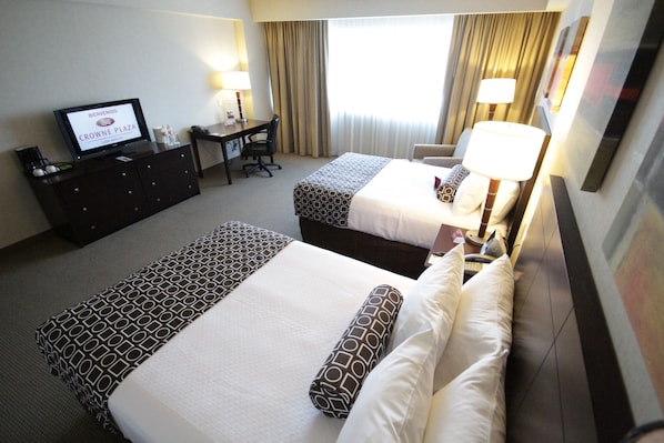 A hotel room with two beds, a desk, a television, and a window with curtains. - Crowne Plaza Leon by IHG (León)
