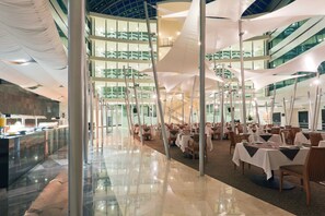 A spacious indoor dining area with high ceilings, multiple levels, and a modern design. - Crowne Plaza Leon by IHG (León)