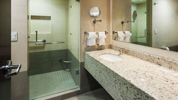 Un bagno moderno con box doccia in vetro, lavabo con piano in granito e uno specchio grande.