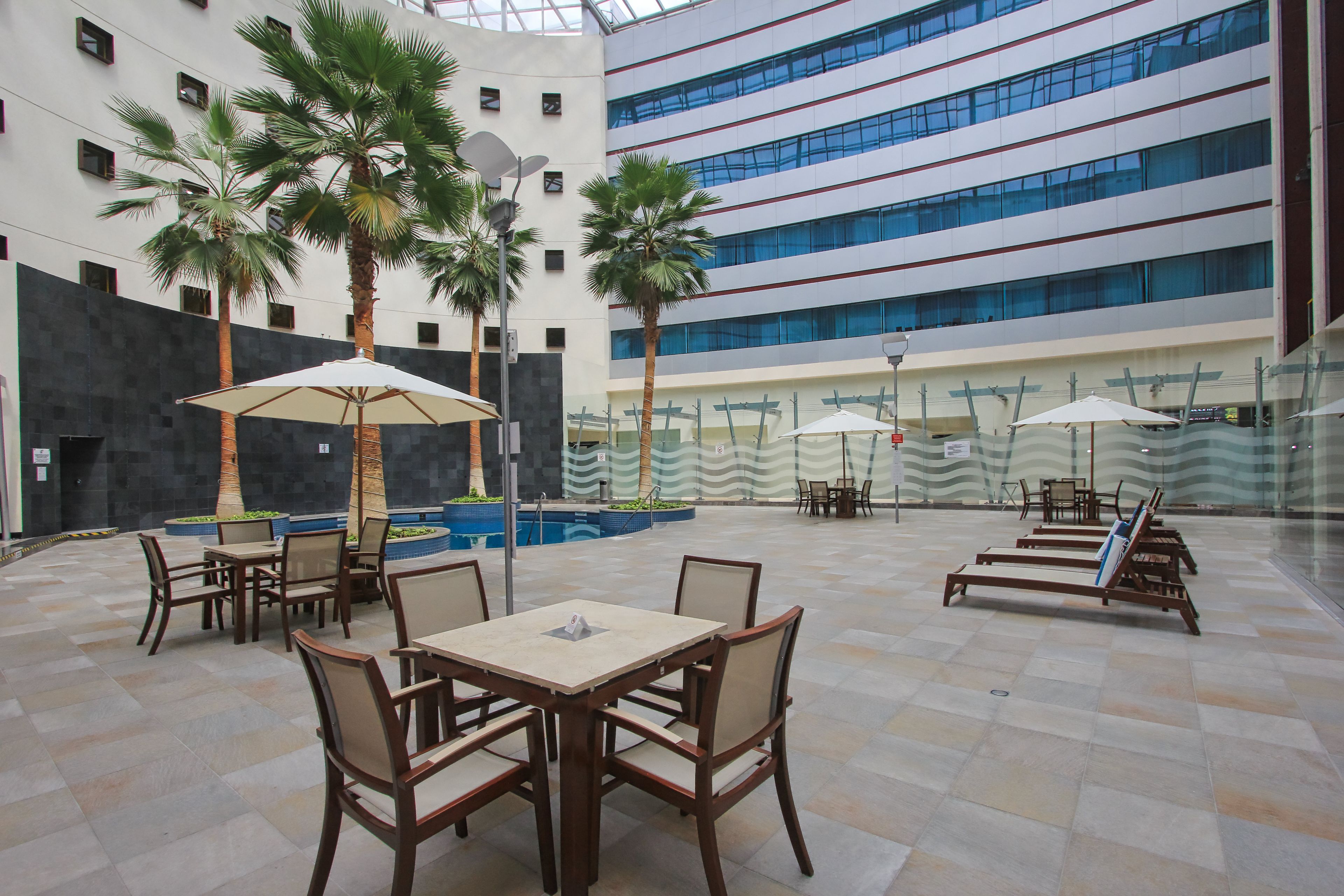 An indoor atrium with a pool, seating areas, and palm trees.