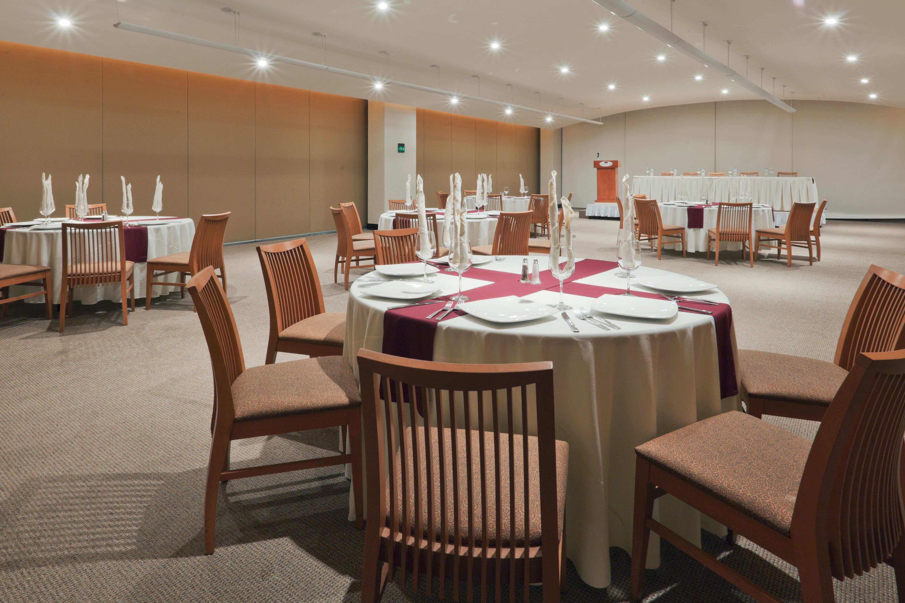 A conference room with round tables, chairs, and a podium.