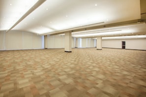 A large, empty conference room with a patterned carpet, white walls, and ceiling lights. - Crowne Plaza Leon by IHG (León)