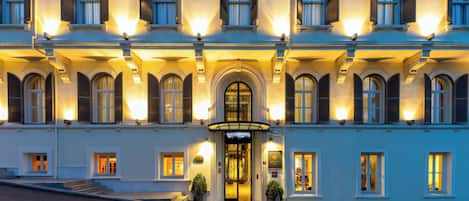 Ein mehrstöckiges Hotel mit einem imposanten Eingang, großen Fenstern und einer gut beleuchteten Fassade.