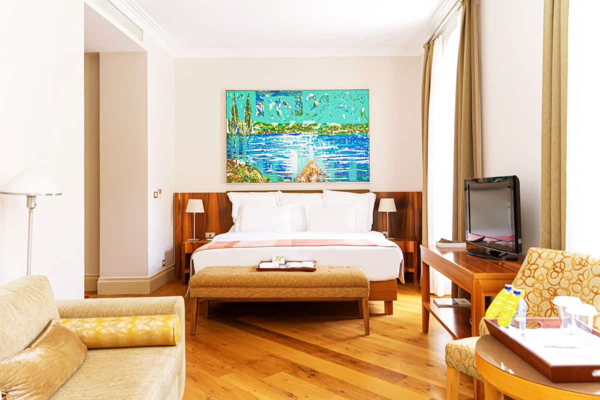 Habitación de hotel con una cama grande, televisión, escritorio y un cuadro en la pared.