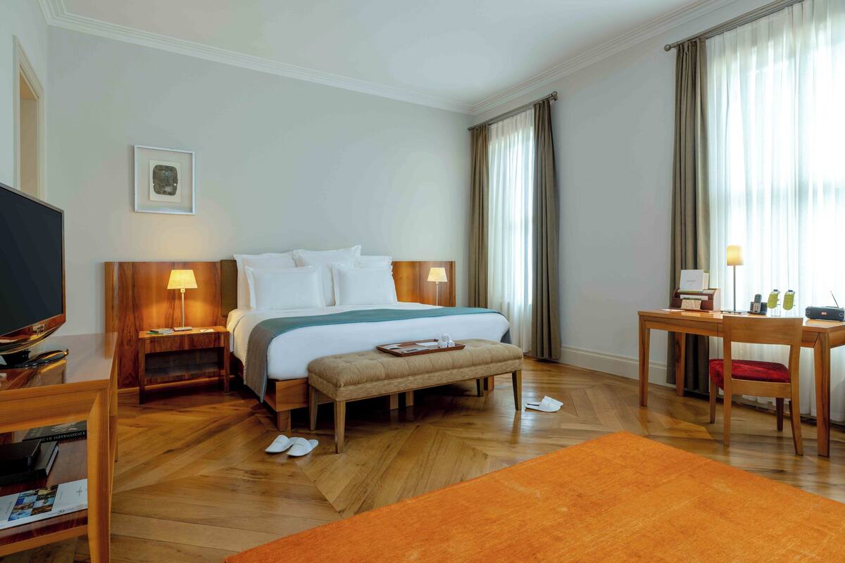 Una habitación de hotel con cama, mesitas de noche, escritorio, silla y televisión.