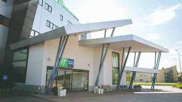 En modern byggnad med en skylt för Holiday Inn Express, stora fönster och ett takförsett utomhusområde med sittplatser.