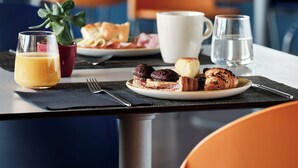 A breakfast setting with a plate of food, a glass of orange juice, a cup, and a glass of water on a table. - Holiday Inn Express Milan - Malpensa Airport by IHG (Somma Lombardo)