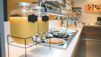 Een buffetopstelling met een koffiehoek, diverse gebakjes en een keuze uit verschillende soorten fruit.