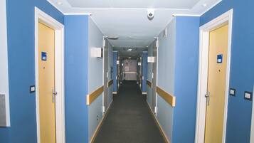 Un pasillo de hotel con paredes azules, puertas de madera y pisos alfombrados.