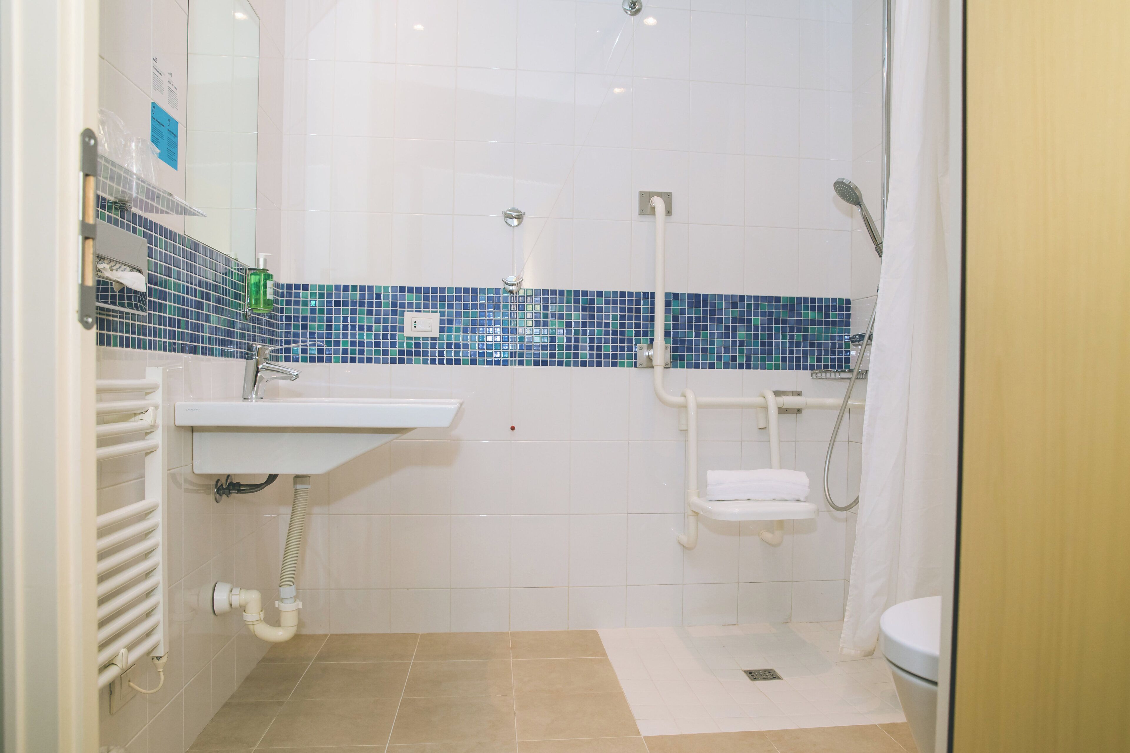 Un baño con un lavamanos blanco, ducha con cabezal de ducha de mano y un inodoro.