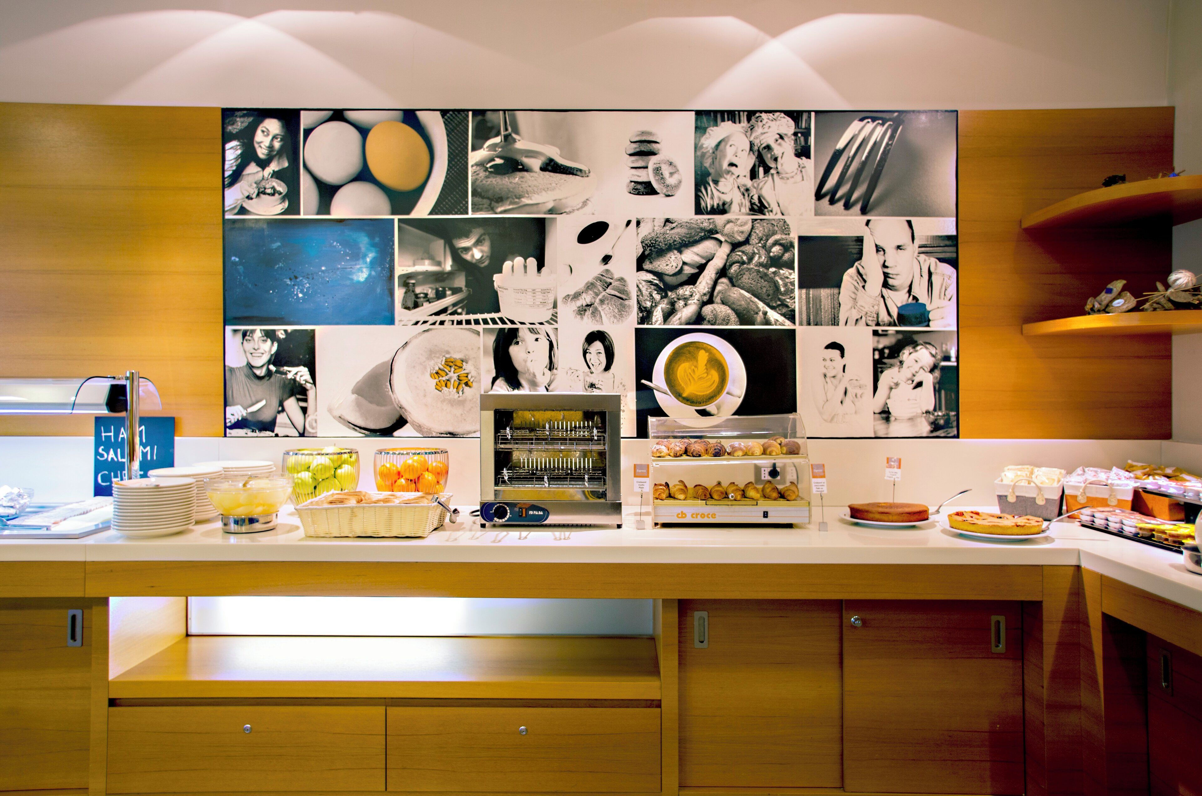 Un bufé de desayuno con diversas opciones de comida y una pared de fotografías en blanco y negro.