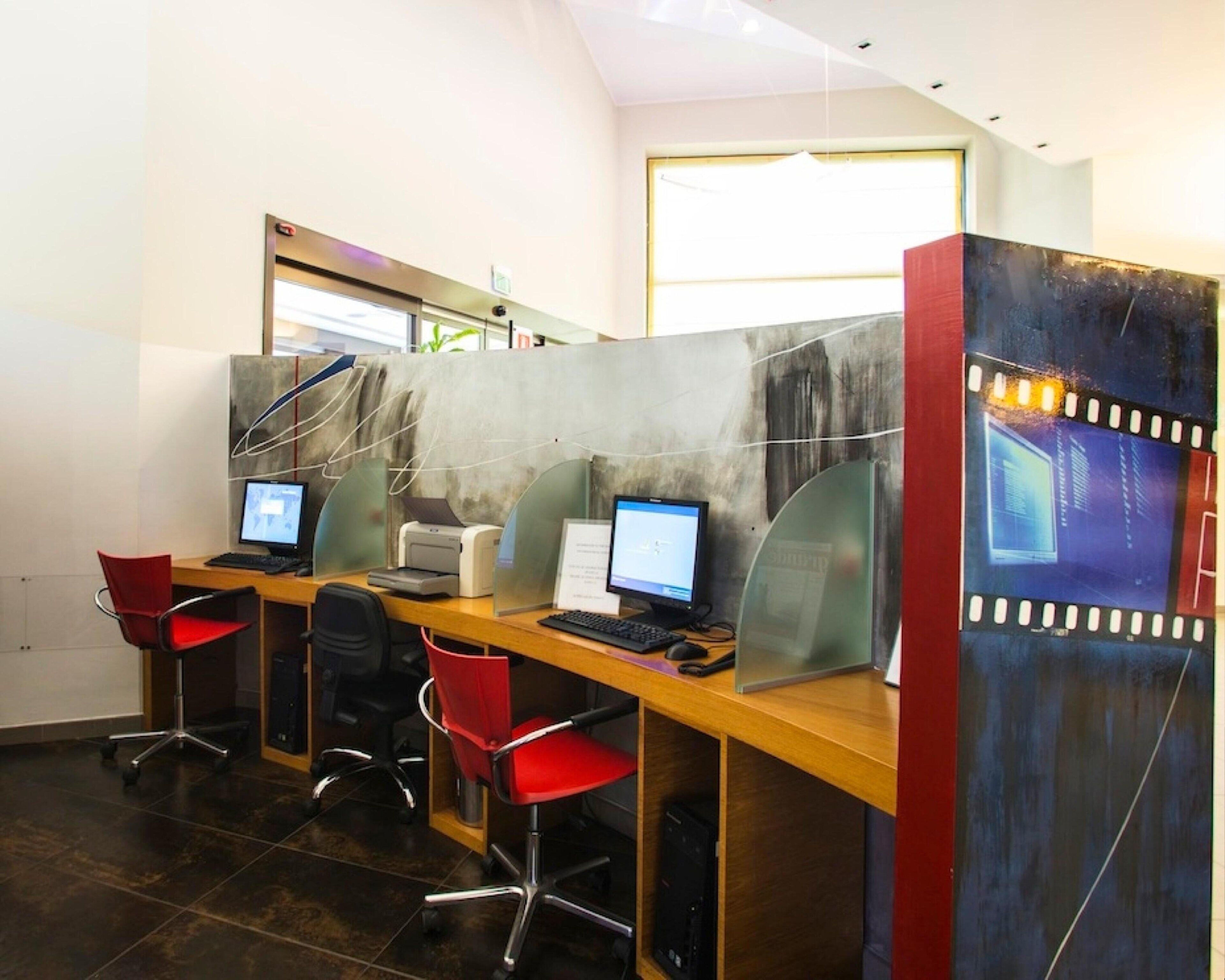 Un espacio de oficina moderno con cubículos, computadoras y sillas rojas.
