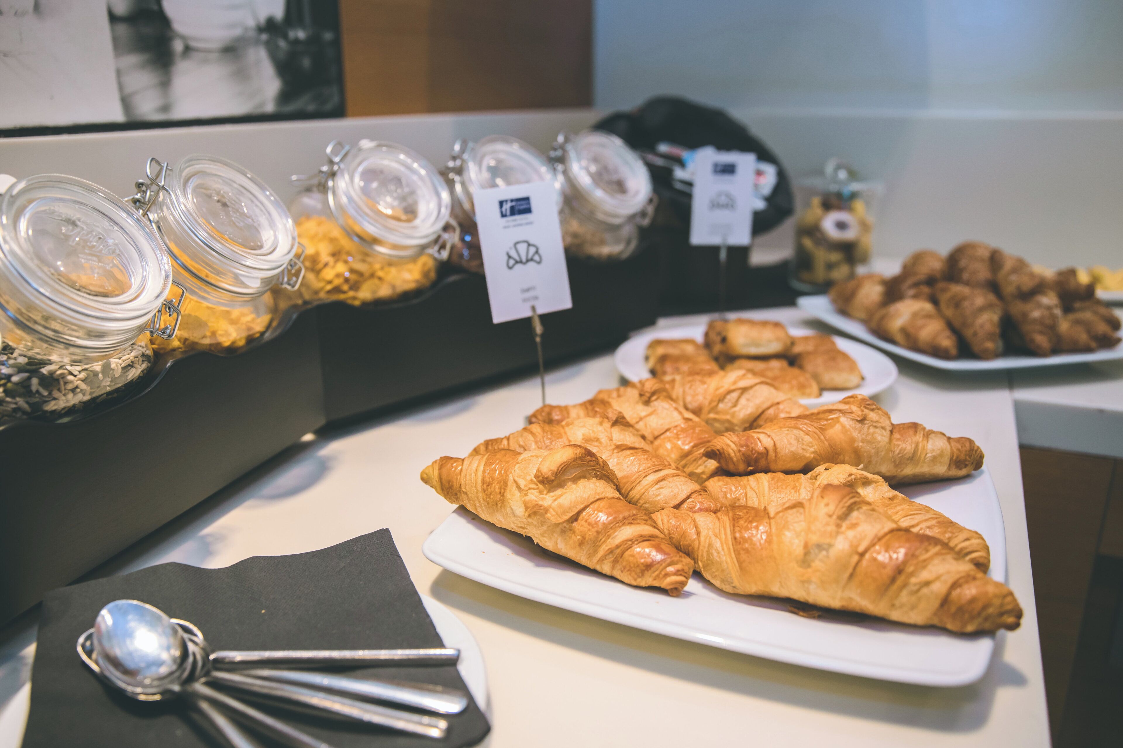 Un buffet proposant une variété de plats, notamment des bocaux de noix et une assiette de croissants.