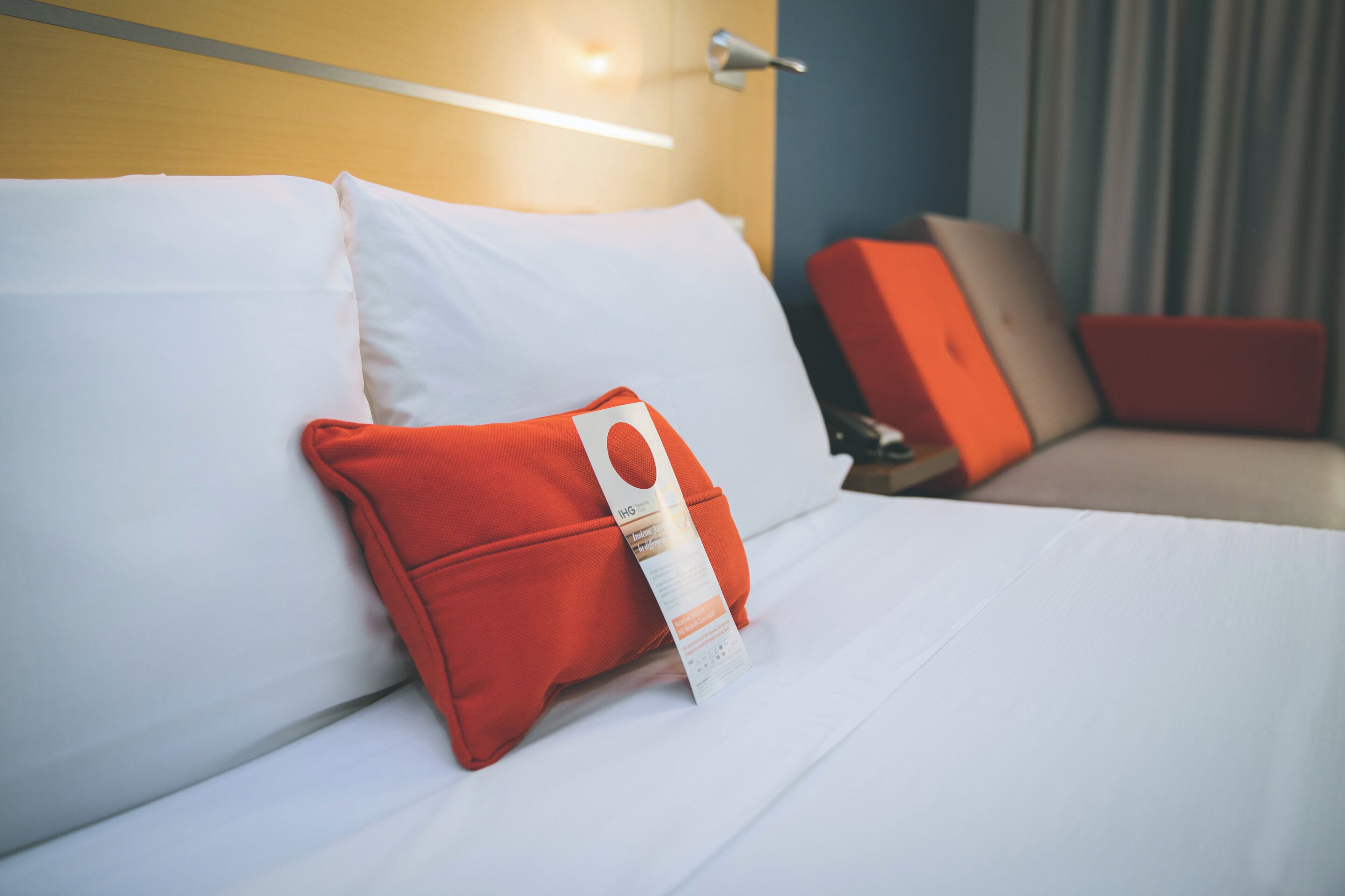 A hotel room with a bed, pillows, and a nightstand.