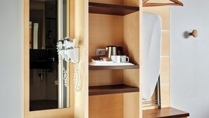 A wooden wardrobe with multiple compartments, a hanging space, and a mirror. - Holiday Inn Express Milan - Malpensa Airport by IHG (Somma Lombardo)
