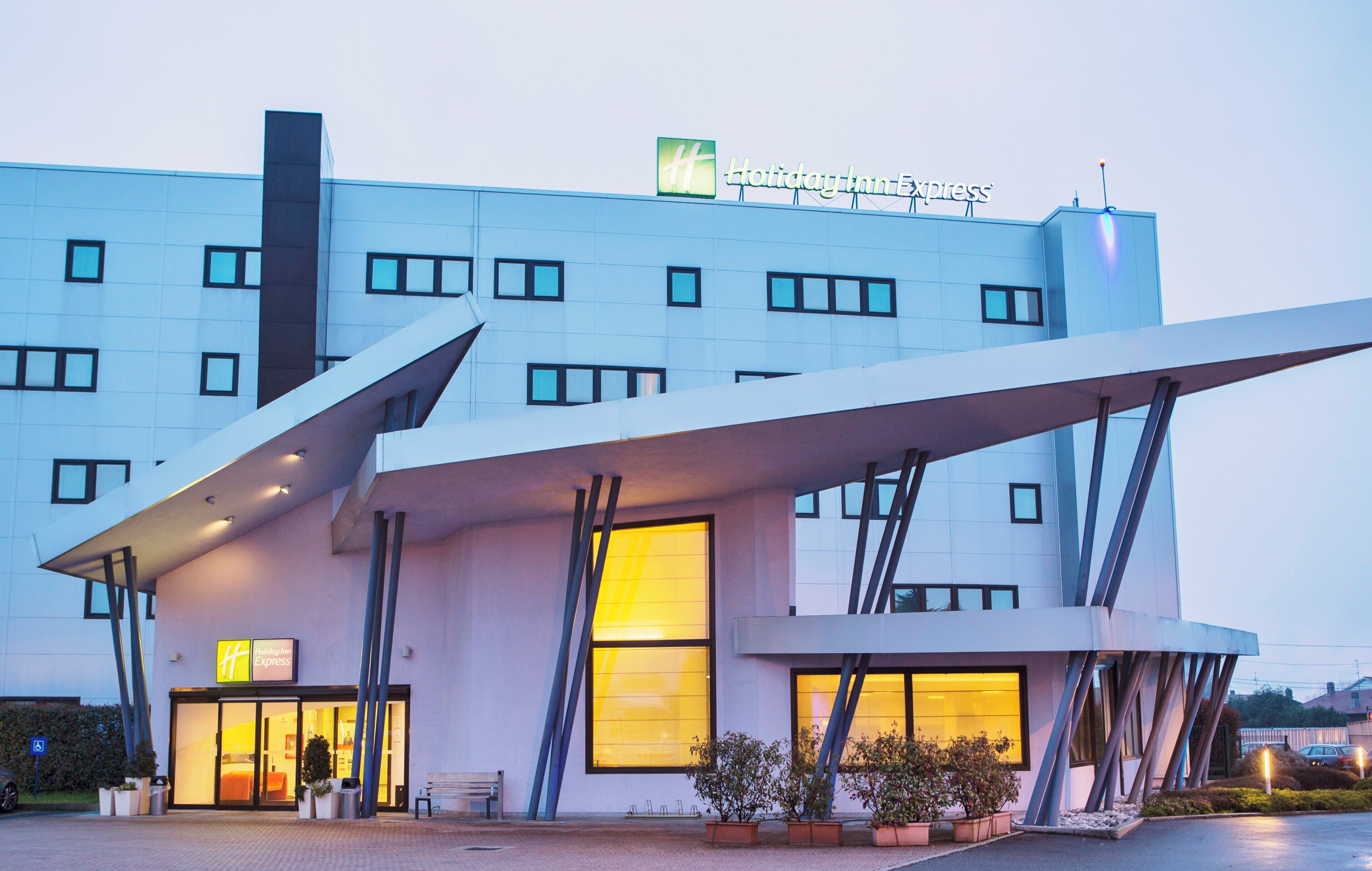 Un hotel Holiday Inn Express con un diseño arquitectónico moderno, que presenta una entrada destacada con un toldo y múltiples ventanas.