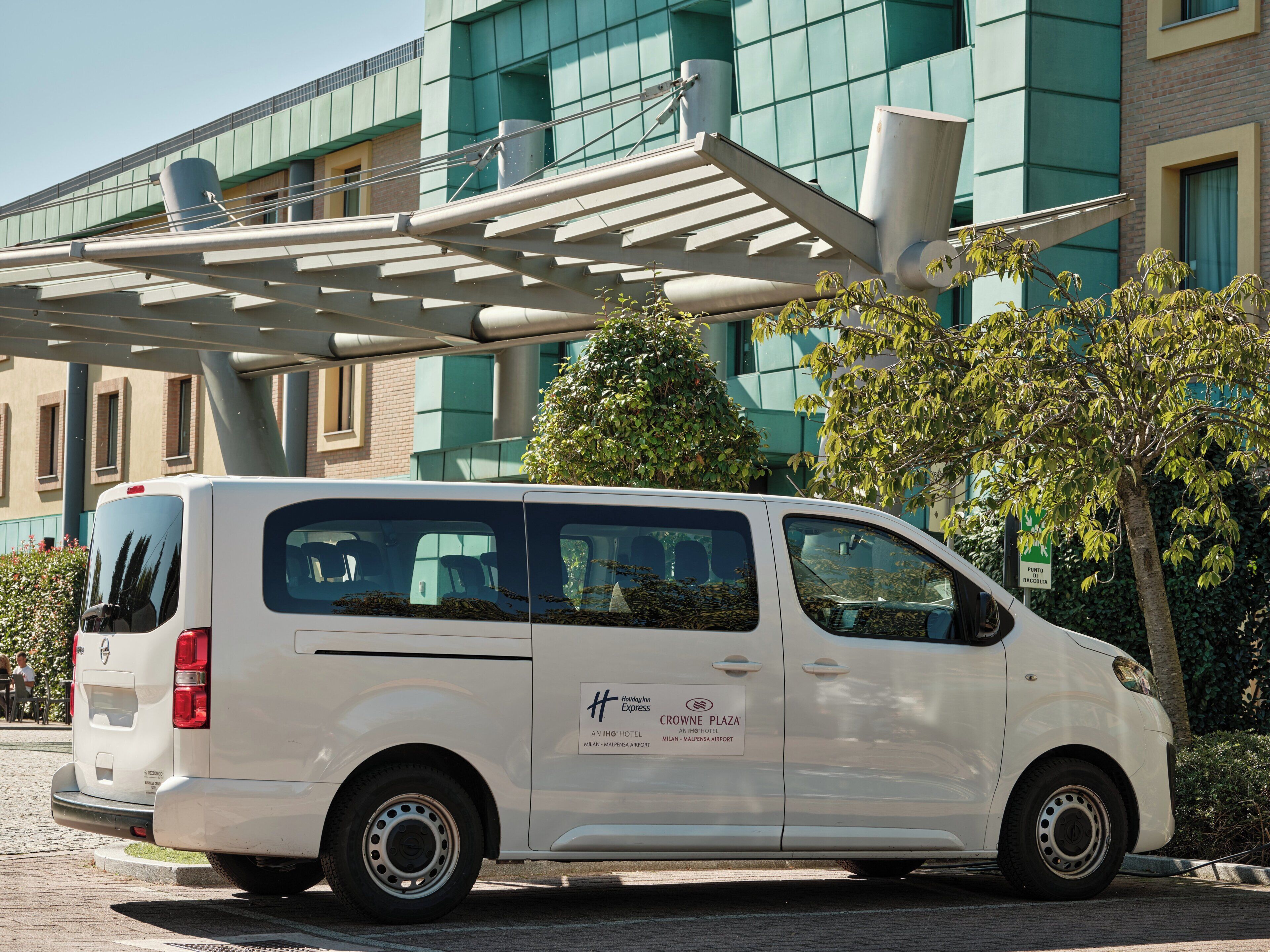 A white van parked in front of a building with a sign that reads 'Crowne Plaza.'