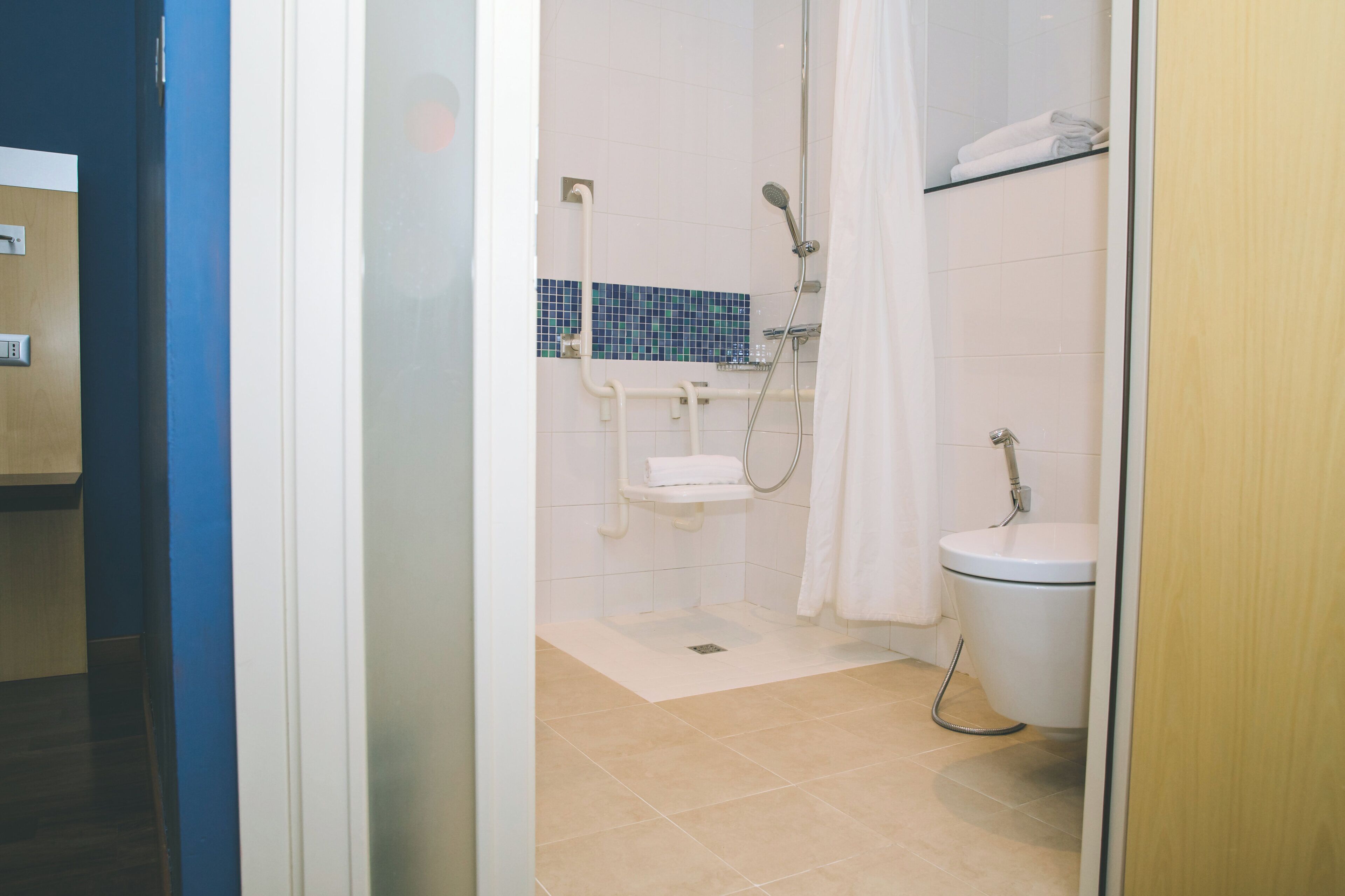 A bathroom with a shower, toilet, and a towel rack.
