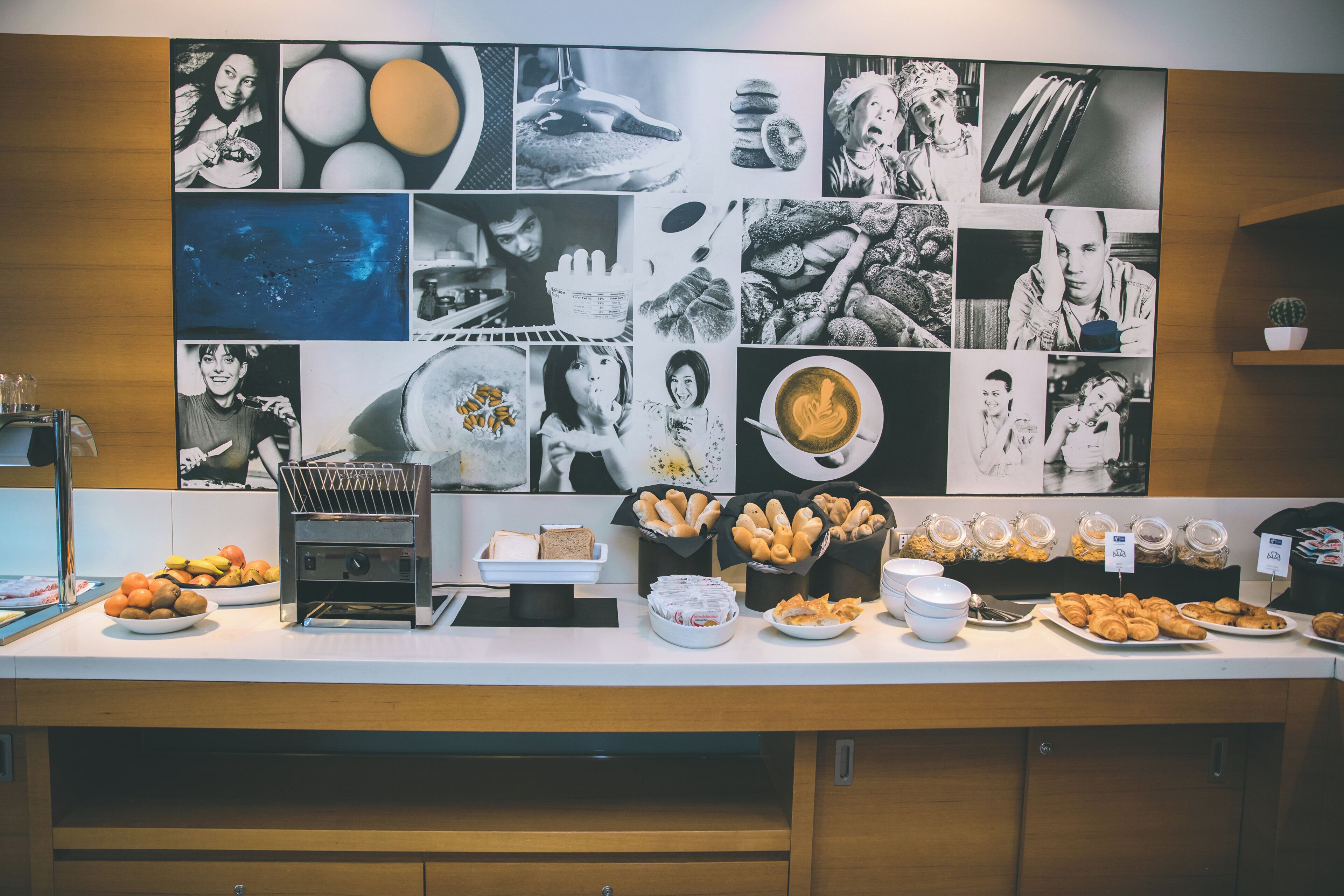 Un buffet de petit-déjeuner proposant une variété de plats et un mur recouvert de photographies en noir et blanc.