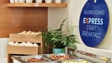 A buffet breakfast area with various food options, a sign for 'BUONGIORNO EXPRESS START BREAKFAST', and a plant in the corner.