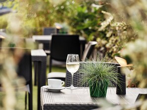 An outdoor table with a glass of white wine, a white cup, and a green plant. - Holiday Inn Express Milan - Malpensa Airport by IHG (Somma Lombardo)