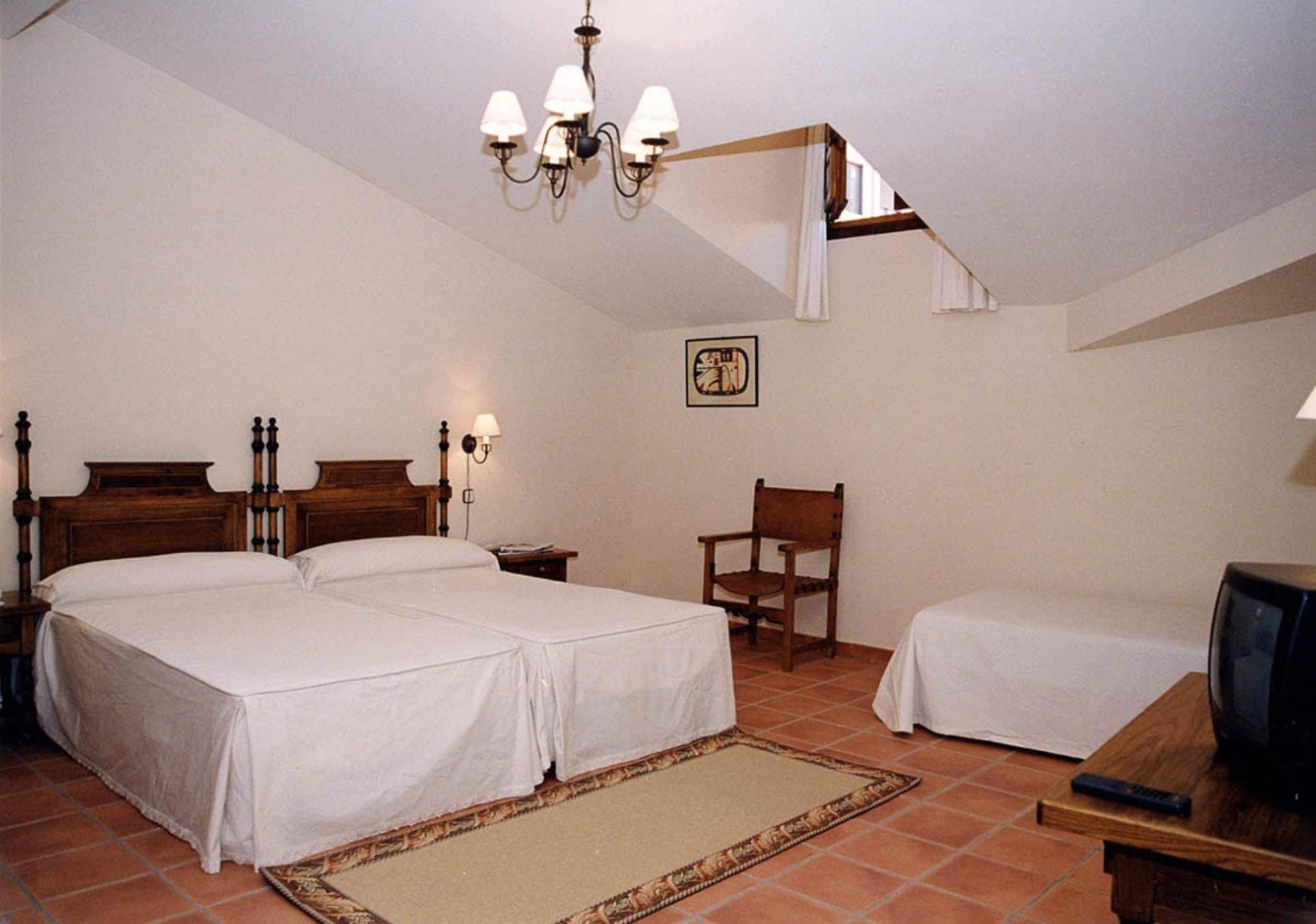 Ein Schlafzimmer mit zwei Betten, einem Sessel, einem Fernseher und einer Chandelier.