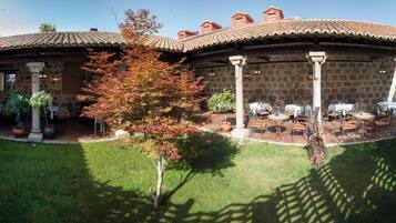 Un patio con edificios de piedra, mobiliario exterior y un césped bien cuidado.