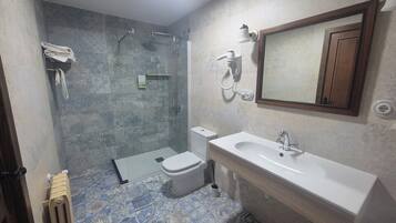 A bathroom with a shower, toilet, sink, and a mirror.