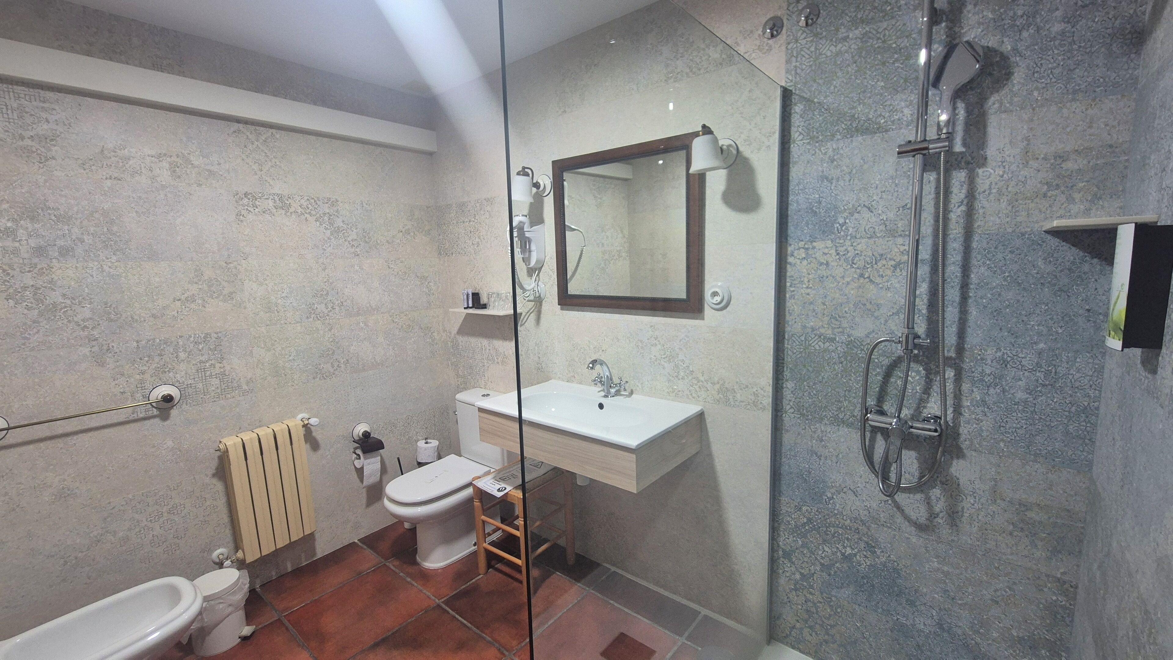 A bathroom with a toilet, bidet, sink, and shower.