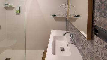 A modern bathroom with a glass-enclosed shower, a white sink, and a mirror with a decorative backsplash.
