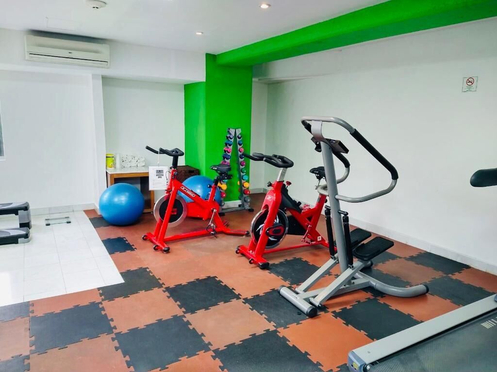A gym with exercise equipment, a blue exercise ball, and a red stationary bike.