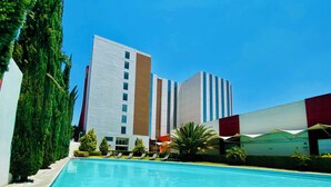 Una piscina con sillones de descanso y un edificio de diseño moderno.