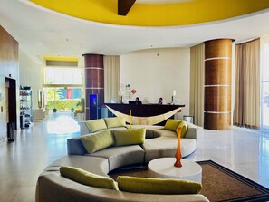 Un moderno vestíbulo de hotel con un mostrador de recepción curvo, un sofá modular y una mesa de centro redonda.