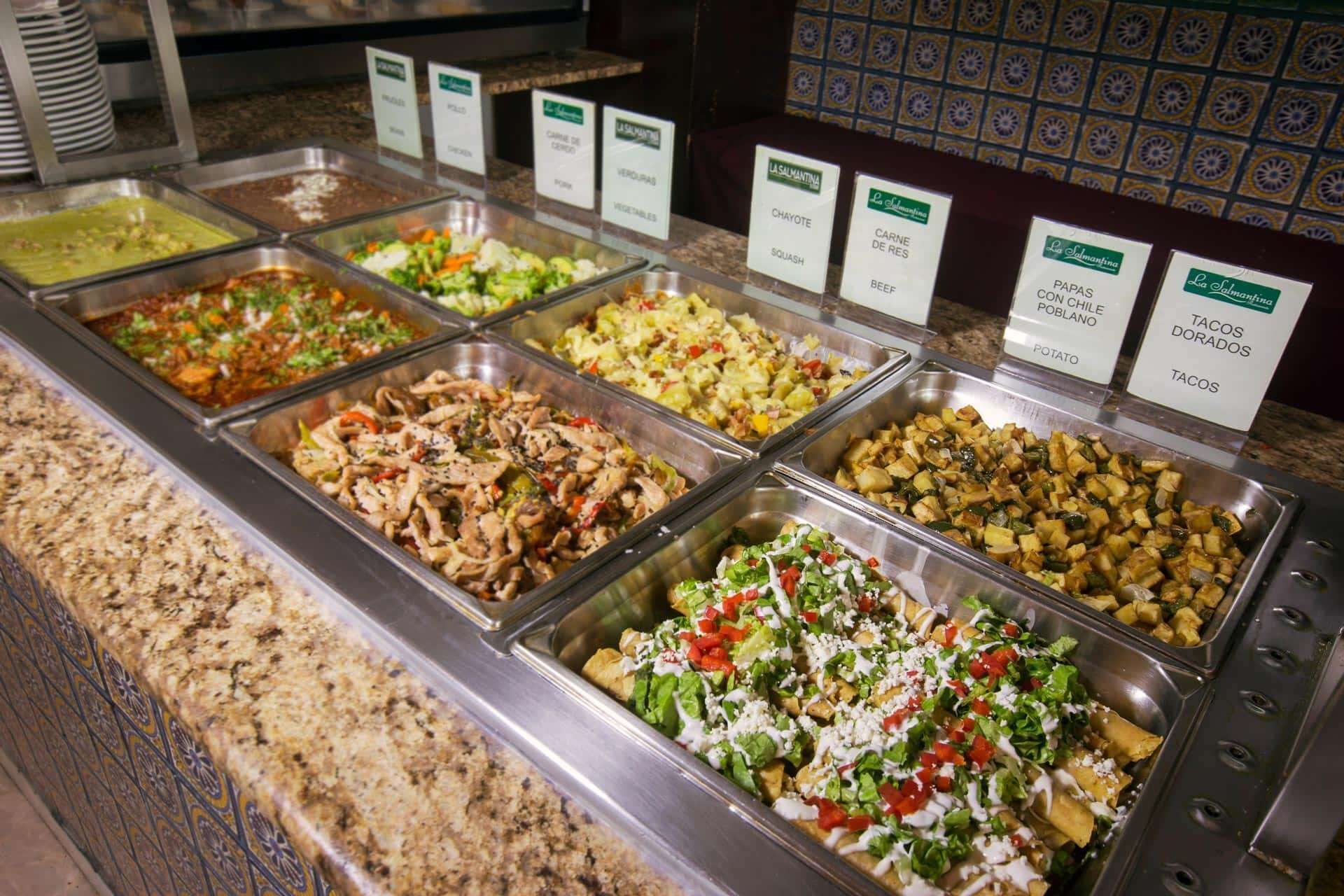 A buffet with various food options including meats, vegetables, and potatoes.