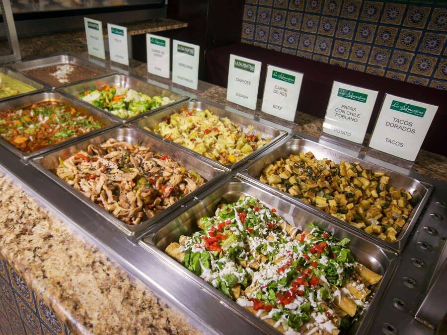 A buffet with various food options including meats, vegetables, and potatoes.