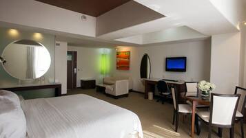 Una habitación de hotel con una cama grande, un escritorio con una silla, un televisor y un espejo.