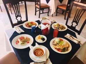 Una mesa de comedor con varios platos, una jarra de bebida roja y una lata de refresco.