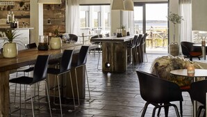A modern dining area with a wooden bar, black chairs, and pendant lighting. - Comwell Roskilde (Roskilde)
