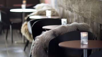 A row of tables with chairs, some with fur throws, in a cafe setting.