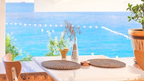 Una mesa con vista al mar, una planta en maceta y elementos decorativos.