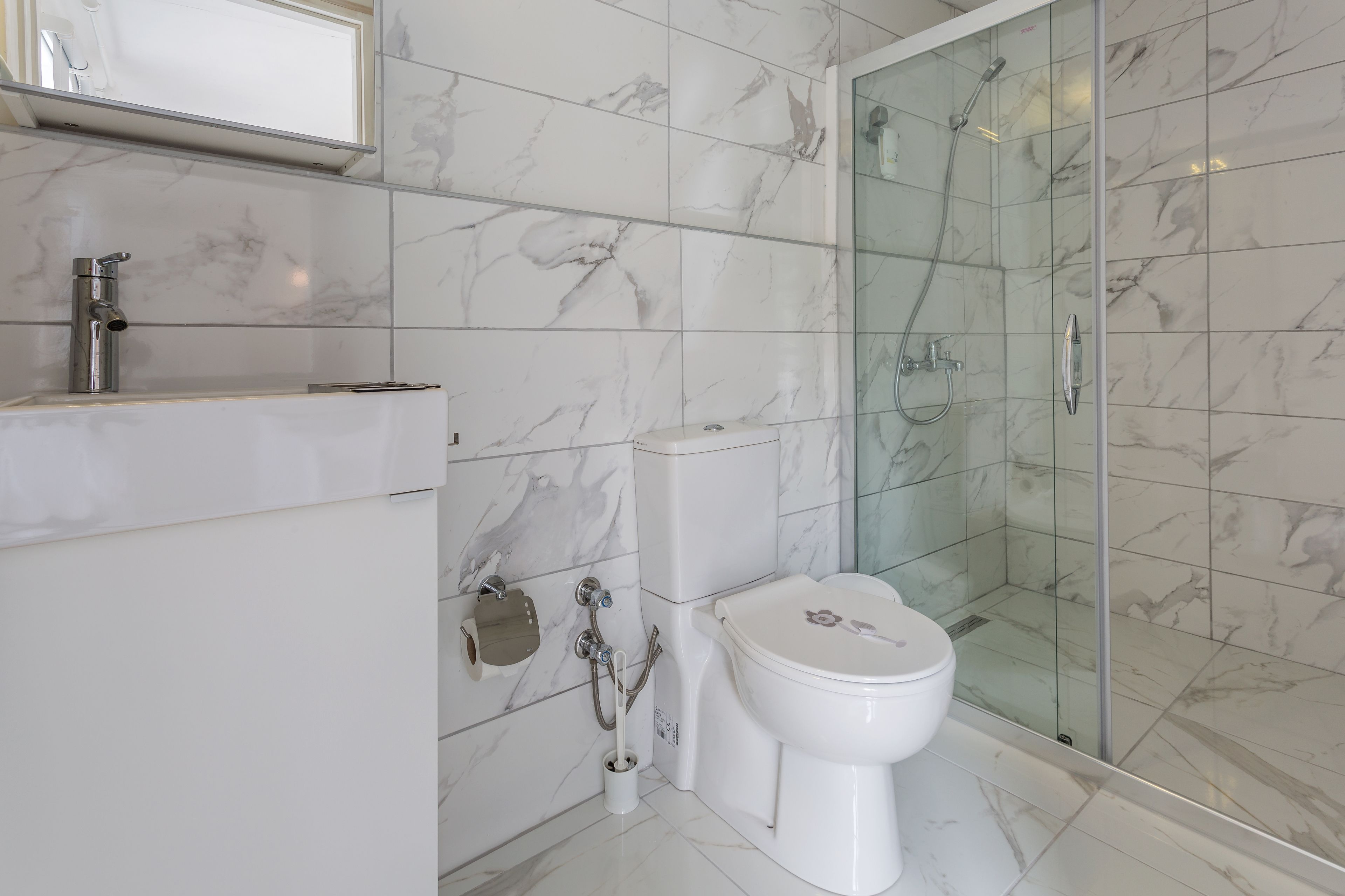 A bathroom with a toilet, a sink, and a glass-enclosed shower.