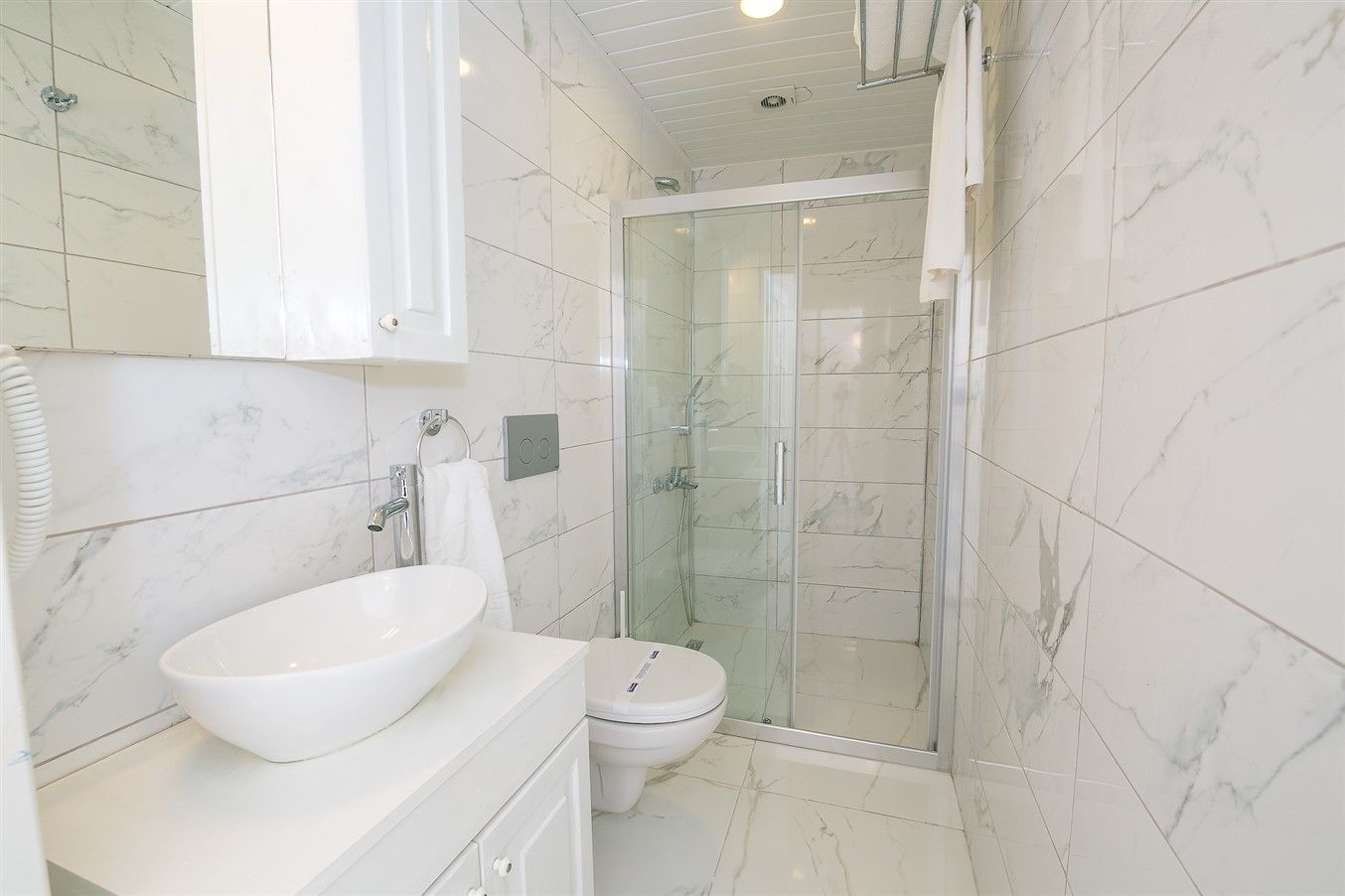 A bathroom with a white sink, toilet, and glass-enclosed shower.